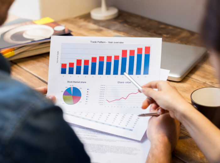 Closeup of businessman and woman discussing on stockmarket document in office